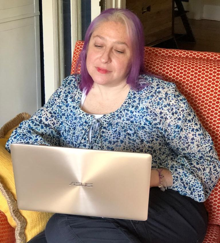 Dori Saltzman sitting in a chair working on her computer